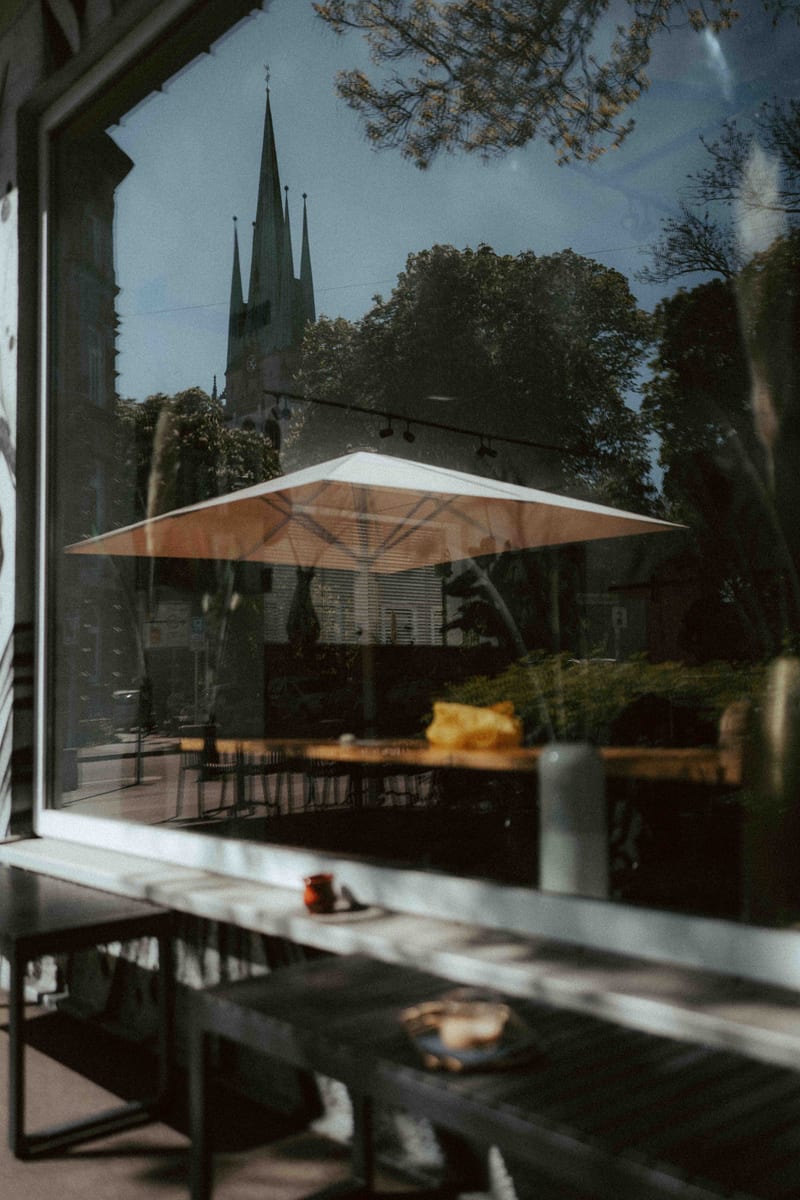 Fenster mit Kirchturm-Reflexion und Kaffeetisch
